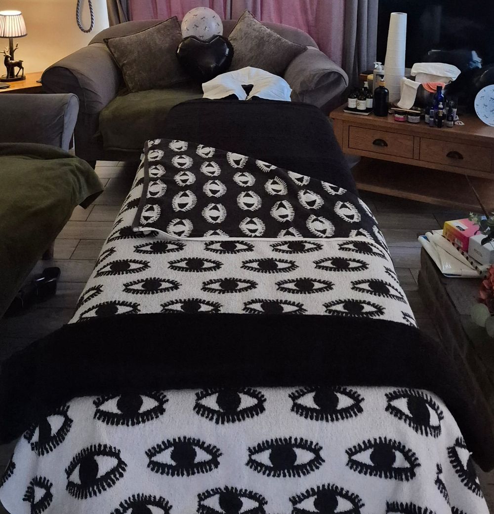 Looking along the treatment couch, dressed in black and cream throws, towards a sofa and a table of products