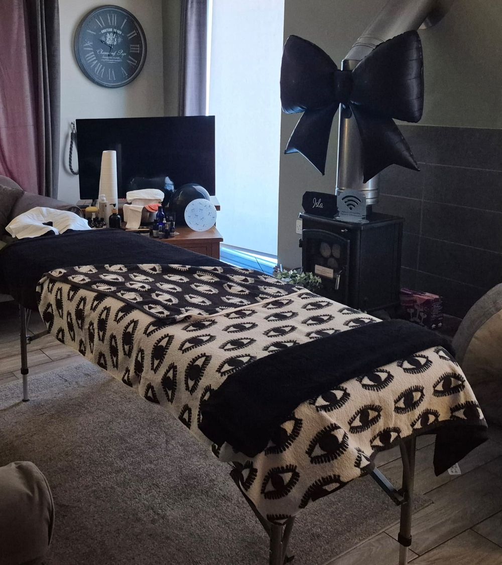 The treatment couch set up in the living room, with a large black bow balloon above a wood-burning stove