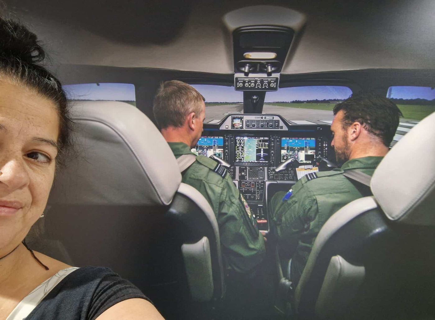 Kathleen beside a wall-sized photograph of two aircrew in a cockpit