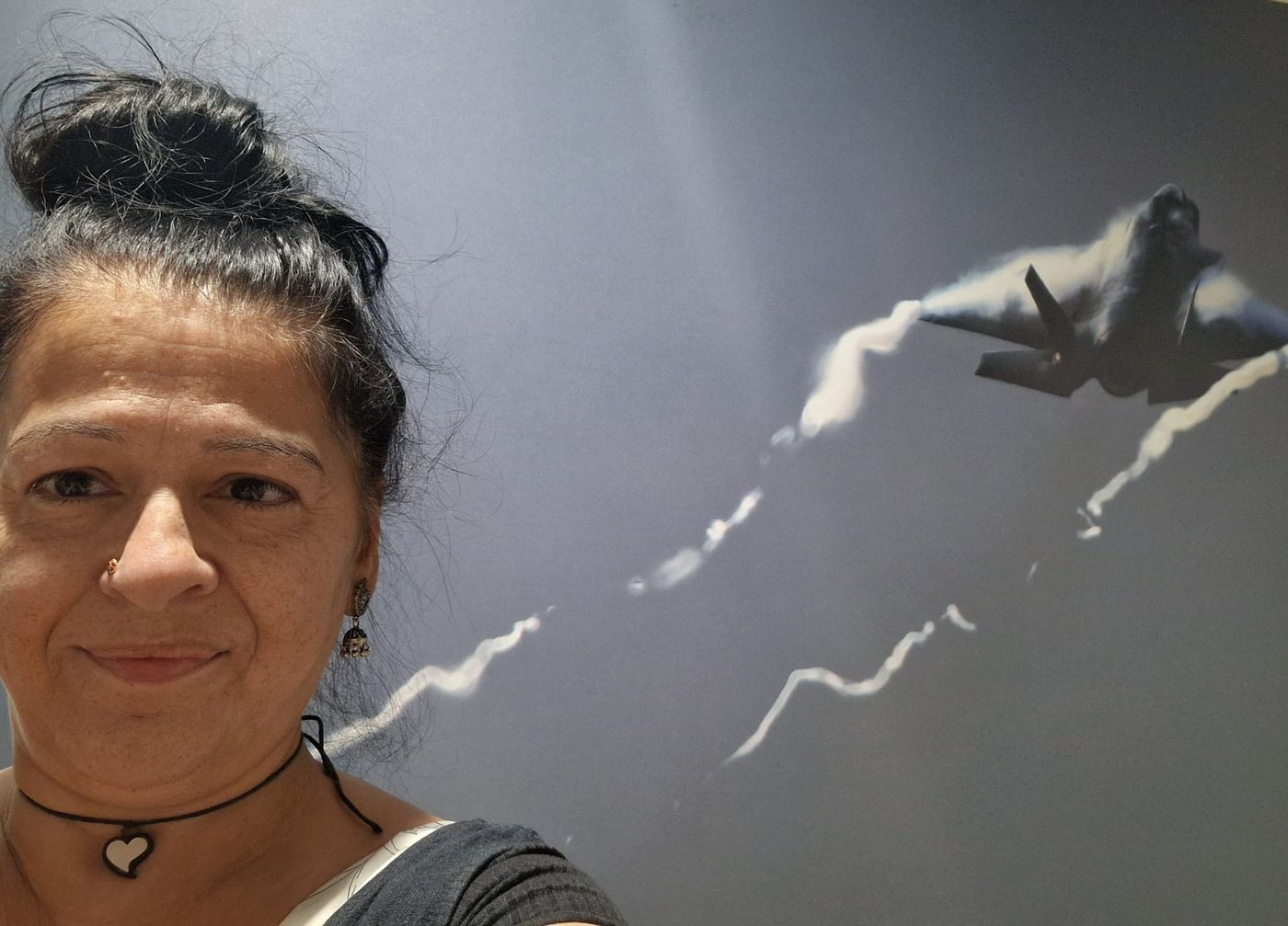 Kathleen in front of a wall-sized photograph of a fast jet at the RAF Wellbeing Day in Lincolnshire