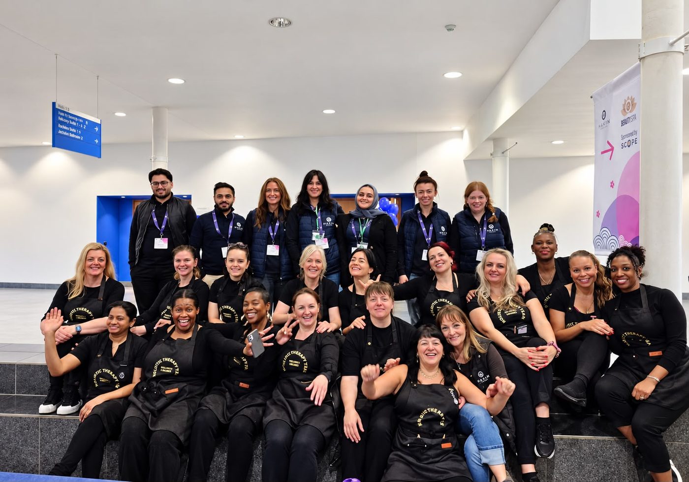 The Holistic Therapy Team in black aprons, together on the steps at a conference venue